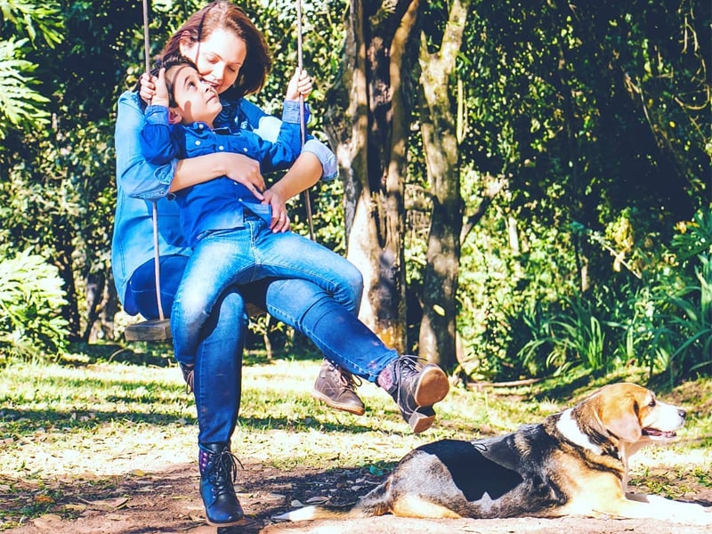 Foto de uma mulher balançando com seu filho e um cachorro deitado no chão