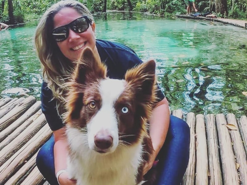 Foto de uma mulher com seu cachorro na nascente areia que canta